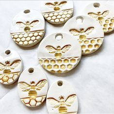 six ceramic bee and honeycomb tags on white background