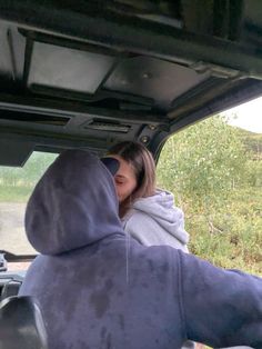 a woman is sitting in the back of a vehicle with her head out the window