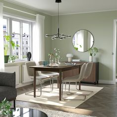 a living room with a table and chairs in front of a large mirror on the wall