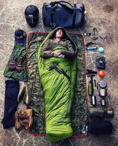 an image of a man sleeping on the ground with camping gear laid out around him