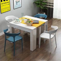 a white table with yellow and blue chairs in front of a poster on the wall