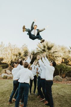 a group of men standing around each other in the middle of a field with one man flying through the air