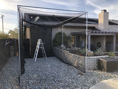 a house that has a ladder in front of it and some rocks on the ground