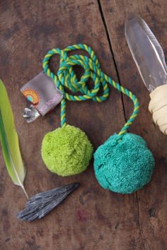 three different colored objects on a wooden table next to a green leaf and a feather