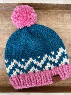 a blue and pink knitted hat with a pom - pom