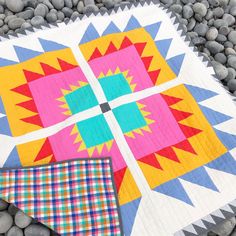 a colorful quilt sitting on top of a pile of rocks