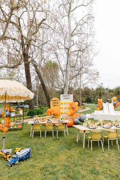 an outdoor party setup with orange and white balloons on the tables, umbrellas and chairs