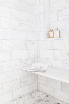 a bathroom with white marble walls and flooring that has hexagonal tiles on the wall