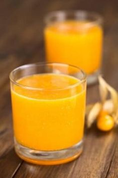 two glasses filled with orange juice on top of a wooden table