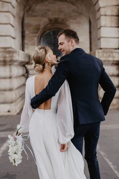 a bride and groom walking together in front of an old building