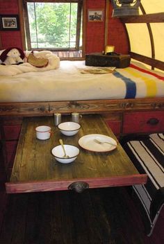 there is a bunk bed with plates and bowls on the table in front of it