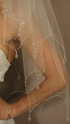 a woman wearing a wedding veil with pearls on it