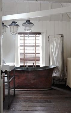 an old fashioned bathtub in the corner of a room with wooden floors and white walls