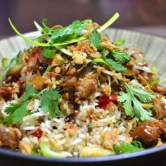 a white bowl filled with rice and meat on top of a table next to a fork