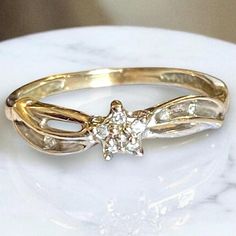 a close up view of a gold ring with a diamond in the center on a marble surface