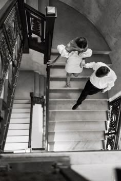 black and white photograph of two people walking up the stairs in an old building together