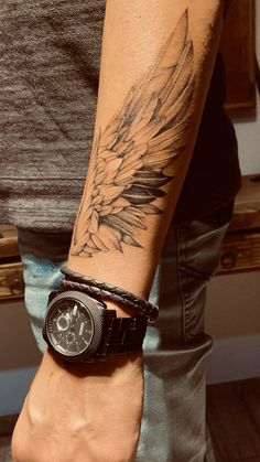 a man with a wrist watch on his left hand and an angel wing tattoo on his right arm