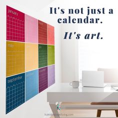 there is a calendar on the wall next to a desk with a laptop and coffee cup