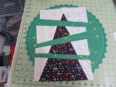 a quilted christmas tree sitting on top of a cutting board next to a ruler