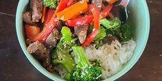 a bowl filled with rice, broccoli and beef