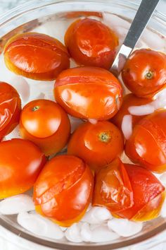 tomatoes and ice in a glass bowl with a knife sticking out of the top one