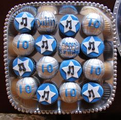 cupcakes decorated with blue and white icing are arranged in a tray