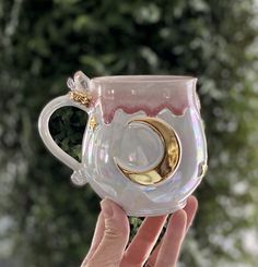 a person holding up a glass cup with a gold ring on the inside and bottom