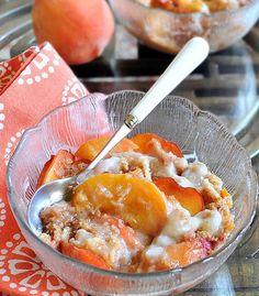 a glass bowl filled with food on top of a metal tray next to two peaches