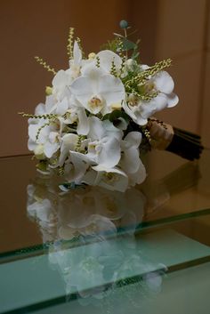 a bouquet of white flowers sitting on top of a glass table