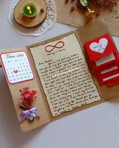 an open book on a table with a candle and other items around it that include flowers