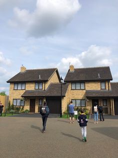 people are walking in front of a large house