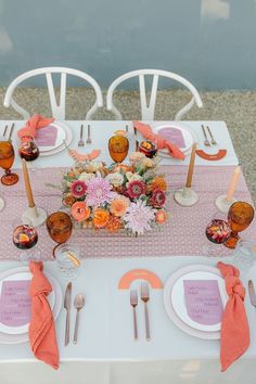 the table is set with pink and orange flowers