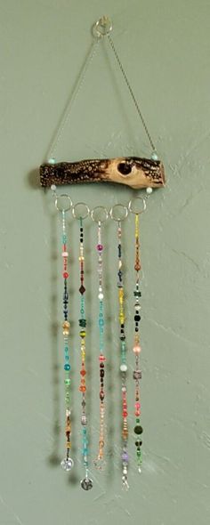 a wind chime with beads hanging from it's side and a piece of wood on the wall