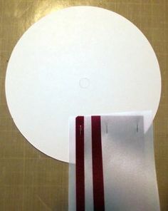 a white object with red stripes on it sitting on a brown table next to a piece of paper