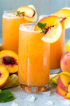 two glasses filled with orange juice and garnished with fresh peaches on the side