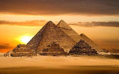 three pyramids in the desert at sunset