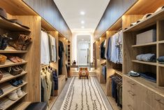 a walk in closet with lots of wooden shelves