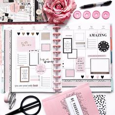 a pink rose sitting on top of a desk next to a planner and some other items