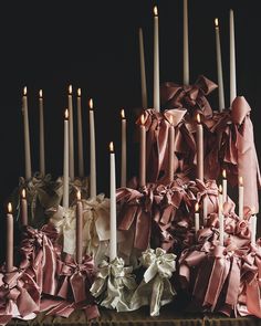 many candles are lit in front of a cake with pink ribbons and bows on it