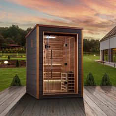 an outdoor sauna is shown with the sun setting in the background and green grass