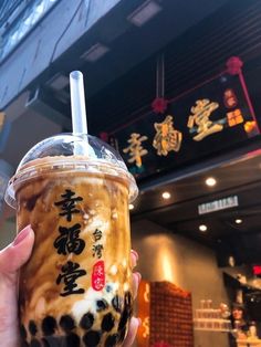 a person holding up a drink with chinese writing on it