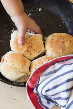 a child is reaching for some bread in a frying pan