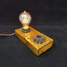 a light bulb sitting on top of a wooden block with a wire attached to it