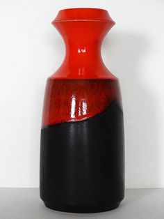 a red and black vase sitting on top of a table