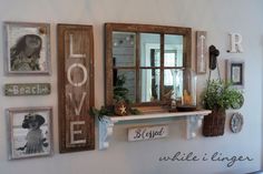 a wall with several framed pictures on it and some plants in the window sill