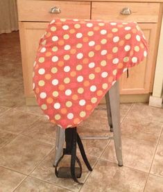 a red and white polka dot chair cover sitting on top of a stool in a kitchen