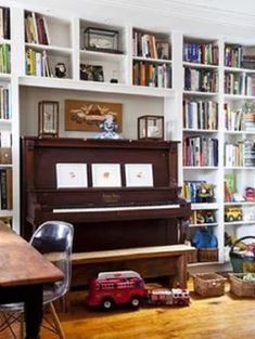 a living room filled with lots of furniture and bookshelves covered in shelves next to a piano