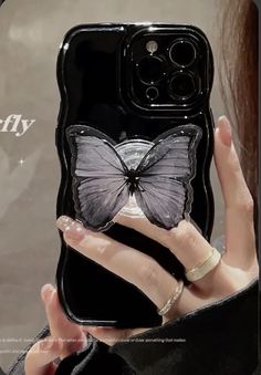 a woman holding up a phone case with a butterfly on it