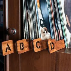 wooden blocks with letters spelling abc and cd's hanging on a wall next to a record player