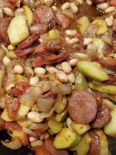 beans, sausage and vegetables are being cooked in a wok on the stove top